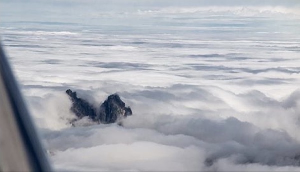 Mountains through the clouds, from the cockpit. (Chapter 2)